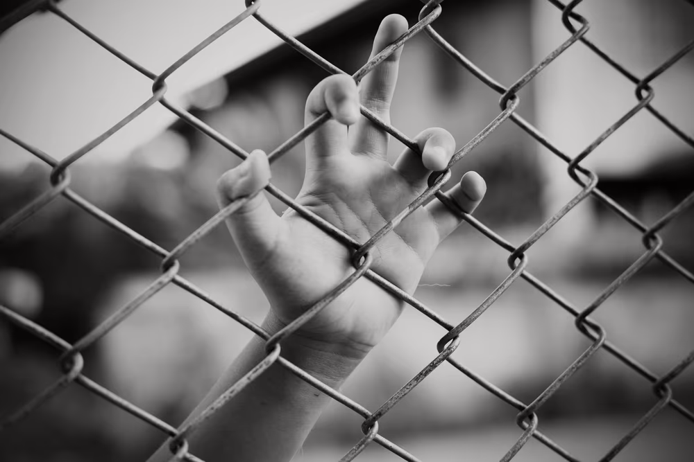 juvenile defense - kids hands are behind a fence in new jersey